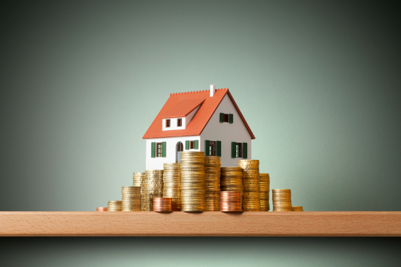 mini house on the table and stack of gold coins