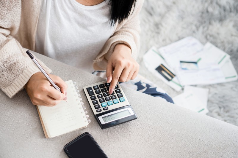 Woman writing a list of debt on notebook