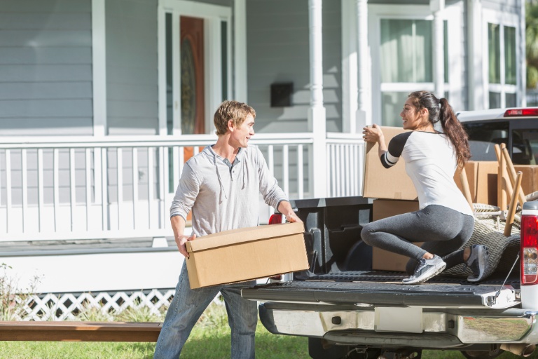 Young couple and pickup truck loaded with boxes